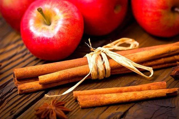 Des morceaux de cannelle à proximité de plusieurs pommes