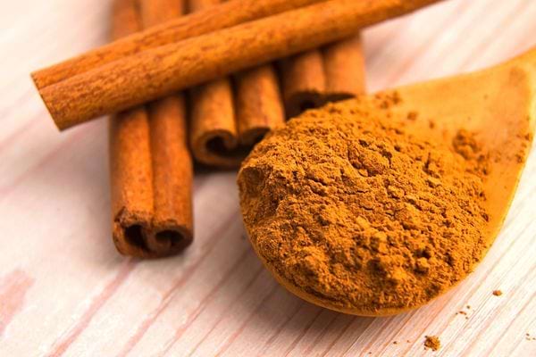 Plusieurs morceaux de cannelle avec une cuillère et de la poudre de cannelle à l'intérieur 