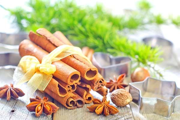 Plusieurs morceaux de cannelle entourée de ruban jaune avec de l'herbe en arrière-plan 