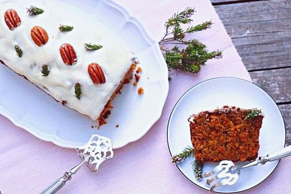 Una torta di carote natalizia vegana con una piccola fetta ritagliata su un altro piatto