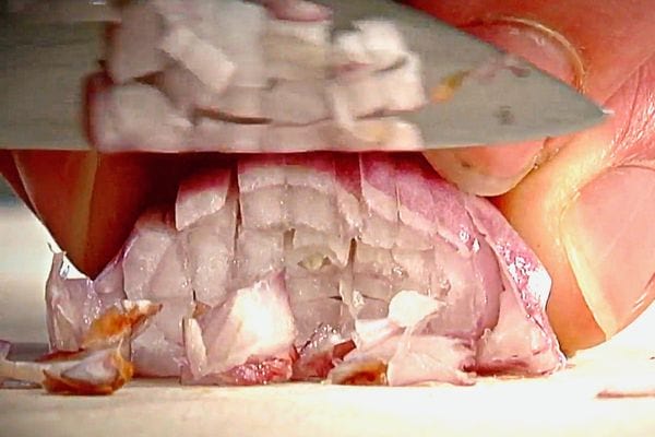 Une échalote qui est en train de se faire couper dans le sens vertical de sa longueur