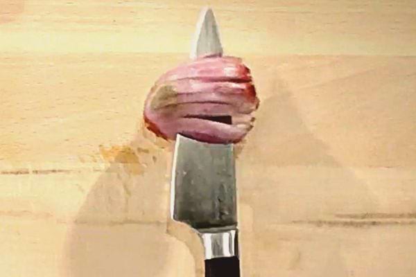 Un couteau qui découpe à l'horizontale une échalote