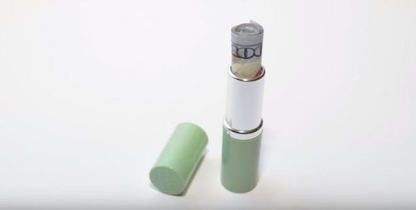 Un dollar introduit dans une boîte de rouge à lèvre verte 