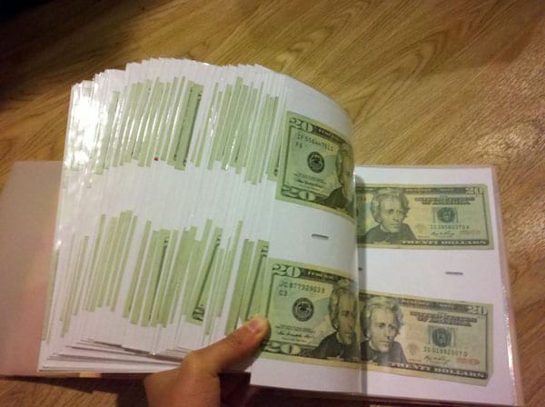 Une personne feuilletant un album photo remplie de dollars 