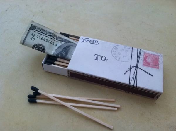 Une petite boîte d'allumettes dans lequel il y a un billet de dollar 