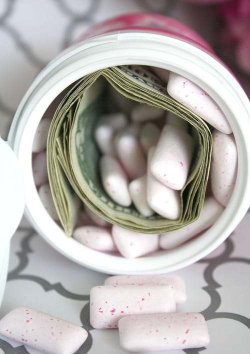 Des dollars qui sont introduit dans une boîte de chewing-gum rose