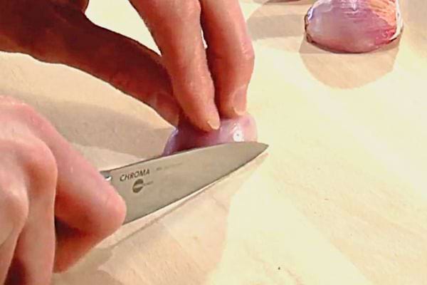 Une échalote posée sur une planche à découper avec un couteau juste à côté