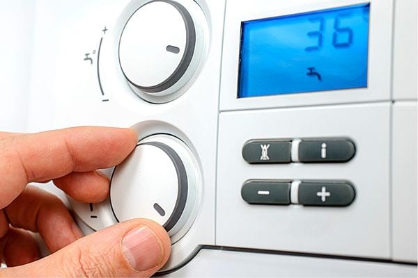 Une personne tournant un bouton sur une chaudière 