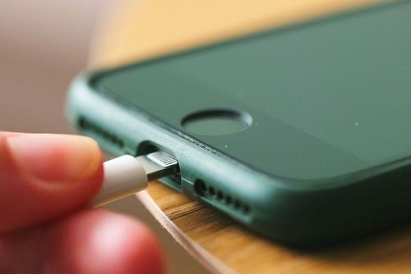Un iPhone noir qui charge avec un fil blanc 
