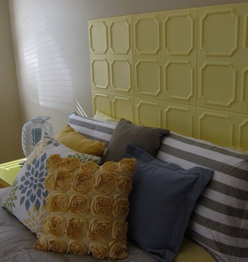 Un lit avec plusieurs coussins et une tête de lit jaune avec des cercles