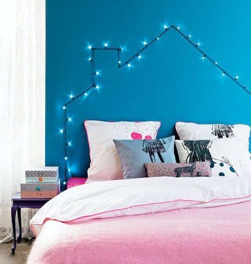 Un lit rose avec des leds en forme de maison au niveau de la tête de lit