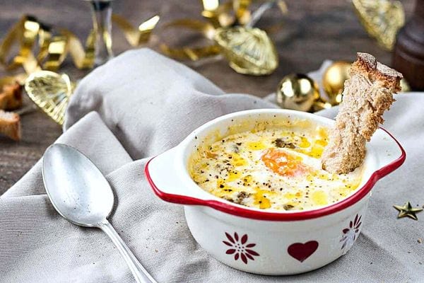 Uno sformato di uova di bosco e dadini di foie gras in un bicchiere con decorazioni natalizie