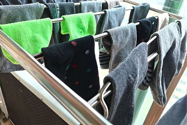 Plusieurs paires de chaussettes qui sont en train de sécher sur un séchoir
