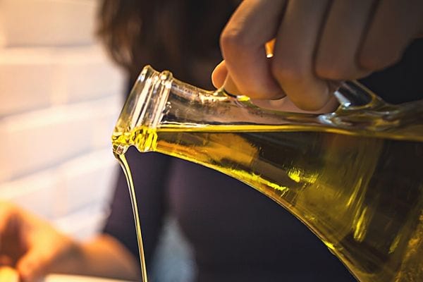Une personne versant de l'huile d'olive