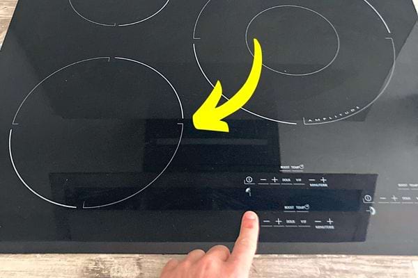 Une main d'une personne s'apprêtant à appuyer sur une plaque de cuisson