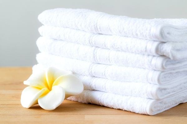 Plusieurs serviettes blanches posées l'une sur l'autre avec une fleur à côté