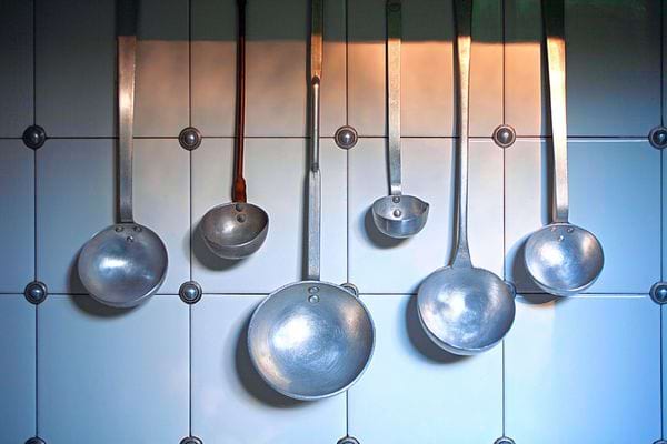 Plusieurs ustensiles de cuisine qui sont suspendues sur un mur dans une cuisine