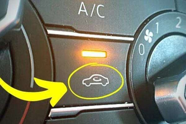 Ein Umluftknopf in einem Auto mit einem gelben Licht direkt darunter