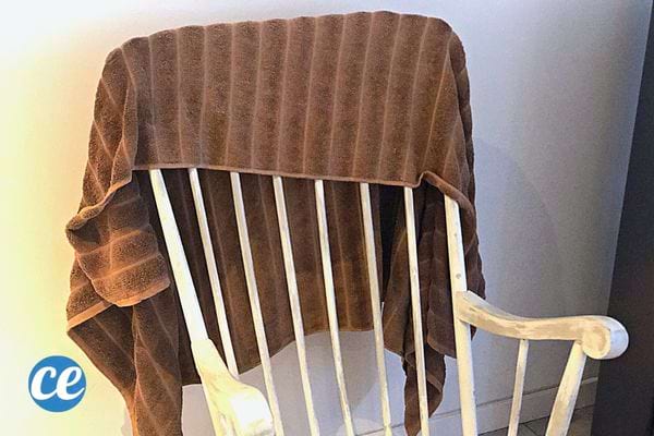 Une serviette marron qui est étendue sur une chaise blanche 