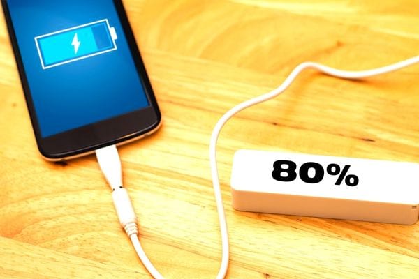 Un téléphone qui charge avec un fil blanc sur une batterie externe blanche à quatre-vingt pourcent