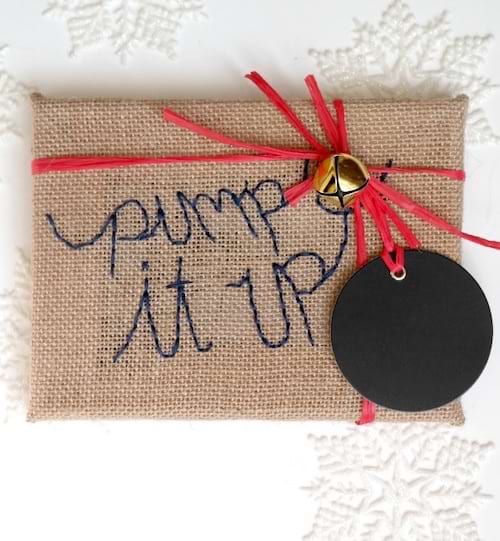 Une toile brodée beige avec un ruban rouge et une petite clochette 