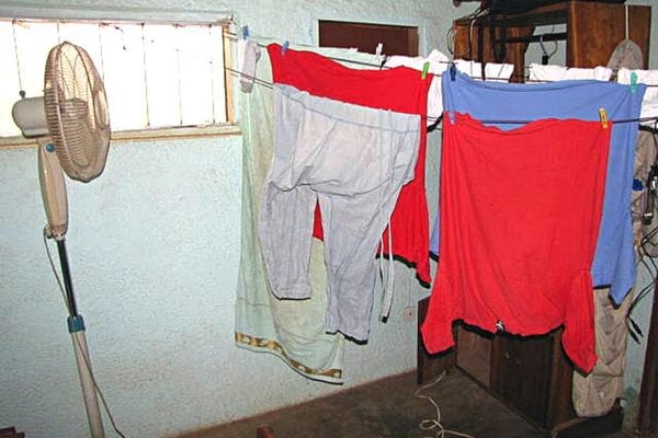 Un grand ventilateur blanc qui est en train de sécher des linges qui sont étendues sur des cordes