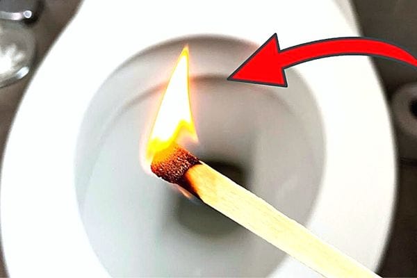 Une allumette allumée au dessus d'une cuvette de WC 