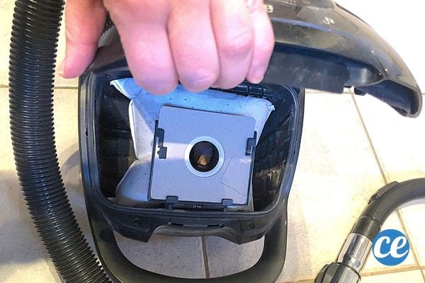 Un aspirateur noir ouvert avec un sac à l'intérieur