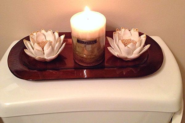 Une bougie parfumée avec deux fleurs de lotus aux extrémités dans des toilettes 