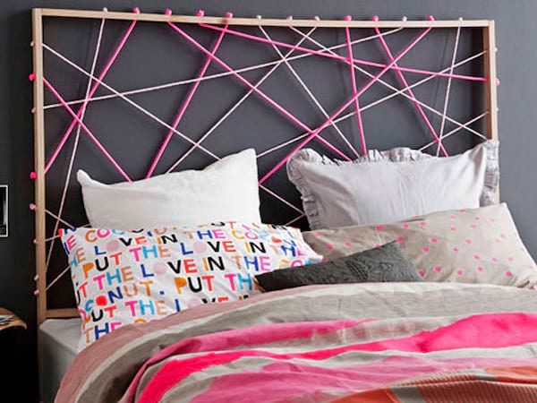 Un cadre avec des cordes roses en tête de lit avec un lit en décoration rose