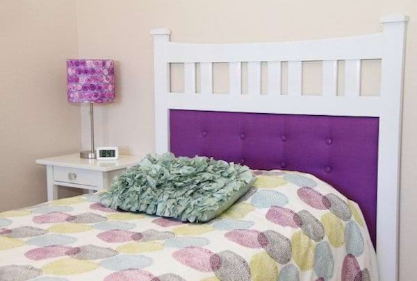 Un lit avec un cadre miroir de commode violet en tête de lit avec une couette avec des ronds