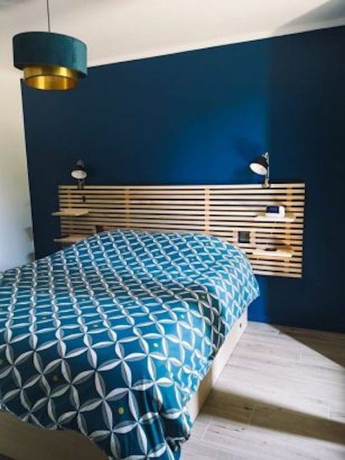 Une chambre décorée en bleu avec des tasseaux en bois à l'horizontale en tête de lit