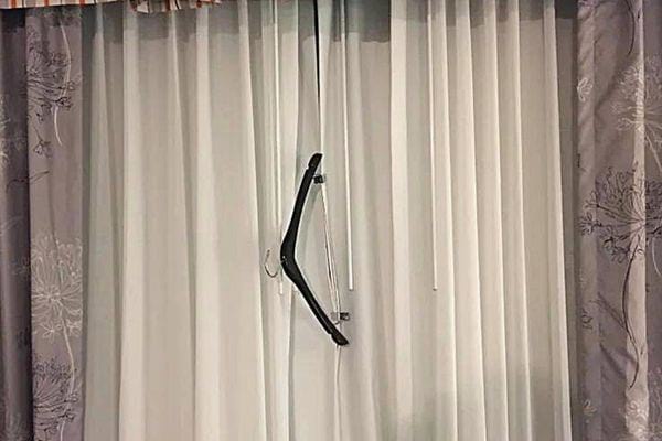 Un cintre noir accroché à des rideaux