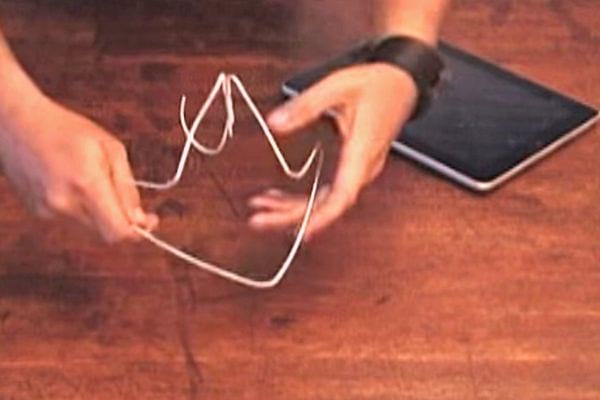 Une personne faisant un support pour un iPad avec un cintre en fer 