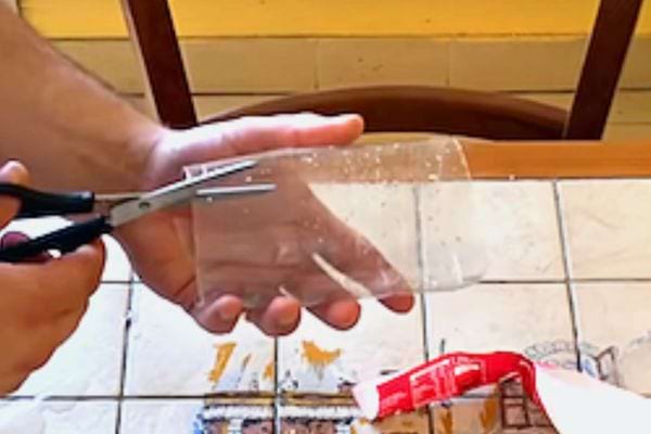 Une personne qui découpe un morceau de plastique à l'aide d'un ciseau