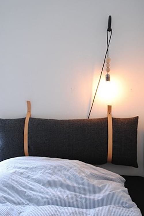 Des oreillers accrochés au mur avec une lampe suspendu à côté du lit
