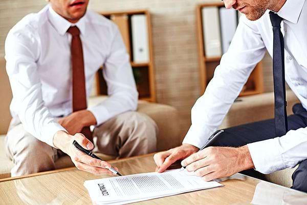 Deux hommes assis en chemise cravate concentré sur une feuille 