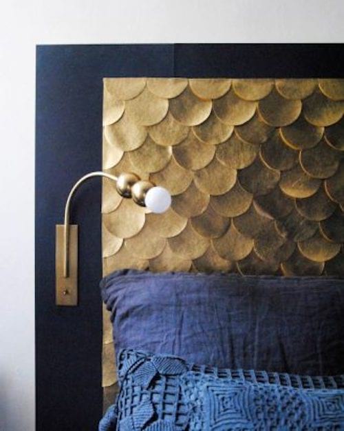 Une tête de lit avec des écailles doré et un lit bleu