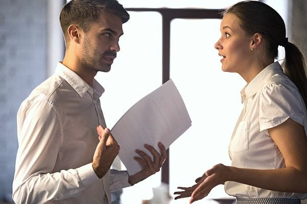 Un homme en chemise blanche qui tient une feuille qui parle avec une femme 