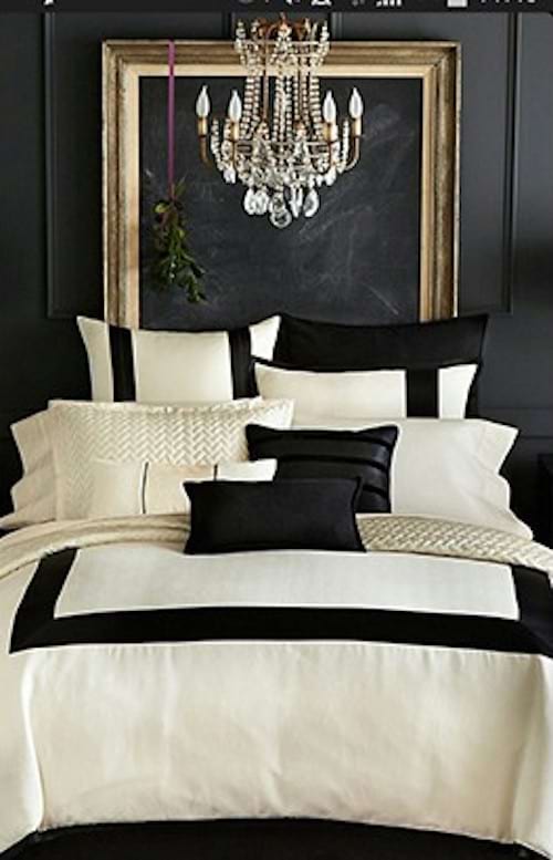 Un lit avec une décoration et plusieurs oreillers noirs et blancs avec un grand cadre doré accroché