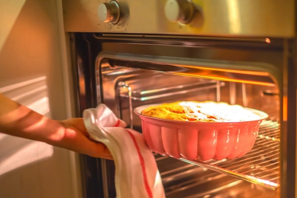 personne qui met un gâteau à cuire au four