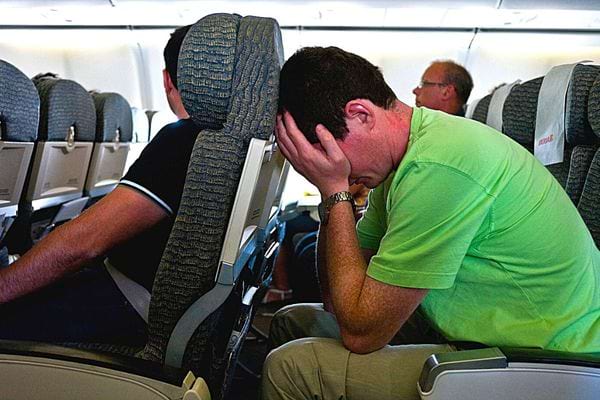 Un homme avec un tee-shirt vert se tenant la tête dans ses mains en avant contre un siège