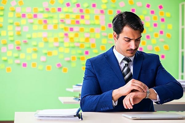 Un homme en costard bleu regardant sa montre 