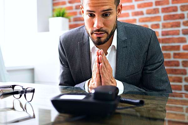 Un homme en costard qui a l'air de supplier devant un bureau 