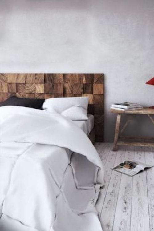 Un lit avec plusieurs briques assemblées au mur pour faire une de tête de lit derrière un lit