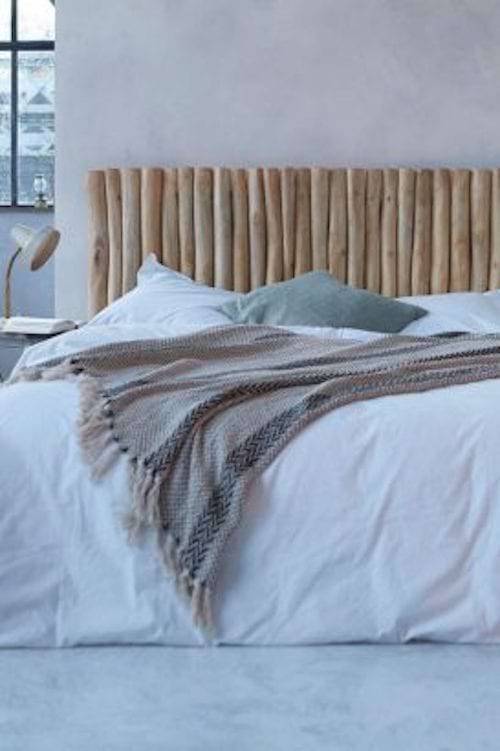 Un lit avec plusieurs bouts de bois en tête de lit