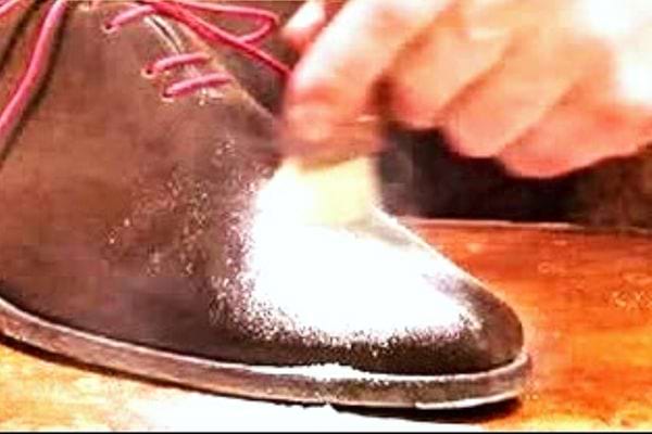 Une personne nettoyant une chaussure en daim à l'aide de mousse à raser 