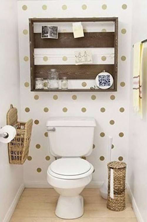 A toilet with a wall painted with golden polka dots 
