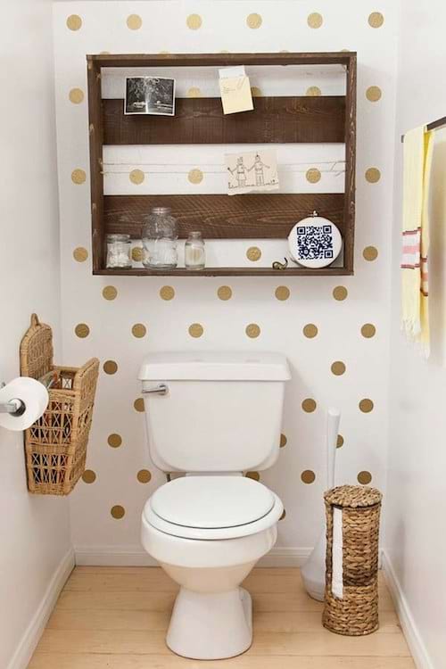 Des toilettes avec un mur peint avec des petits pois doré