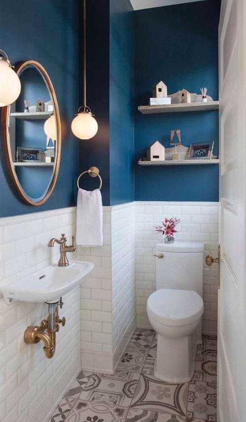 Un mur bleu avec du carrelage blanc juste en dessous dans des toilettes